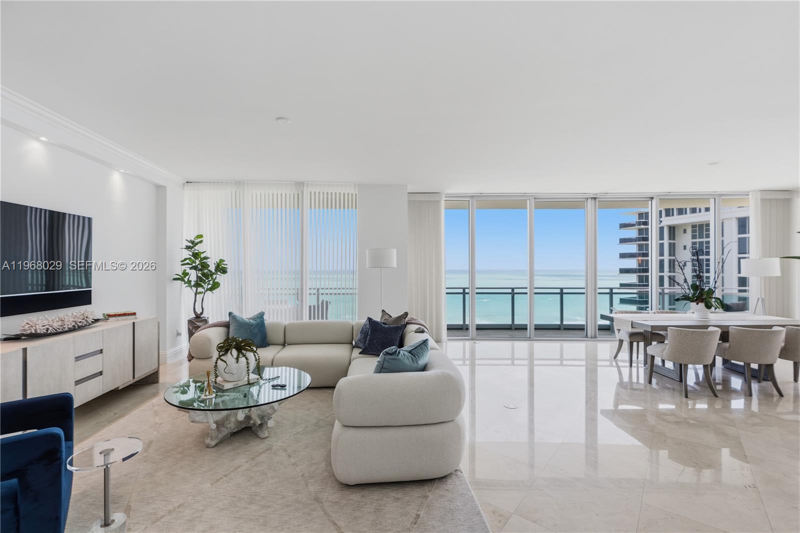 A bright living and dining area features white furniture, marble floors, and ocean views — 10295 Collins Ave # 801, Bal Harbour FL 33154, BAL HARBOUR, FL