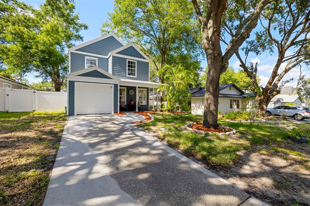 A two-story blue house with a white garage and a concrete driveway under large trees — 7508 WAKULLA DRIVE, TEMPLE TERRACE, FL