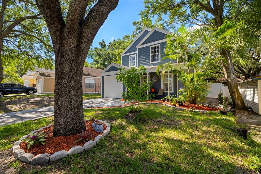 A two-story blue house with a front porch, a garage, and a large tree — 7508 WAKULLA DRIVE, TEMPLE TERRACE, FL
