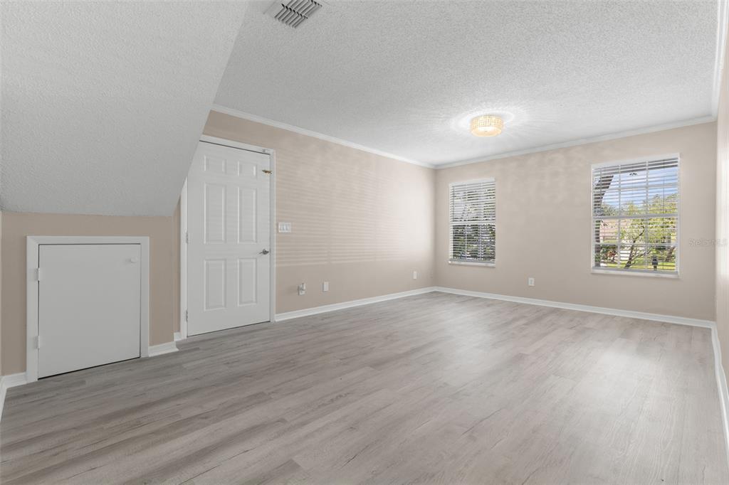 A living room with light wood-look flooring, a beige sofa, two armchairs, and a rug — 7508 WAKULLA DRIVE, TEMPLE TERRACE, FL