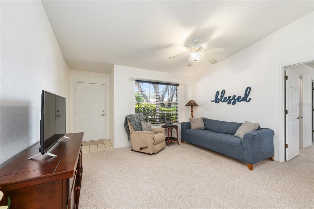 A living room features a blue sofa, a tan recliner, and a television on a console — 8038 SW 108TH LOOP, OCALA, FL