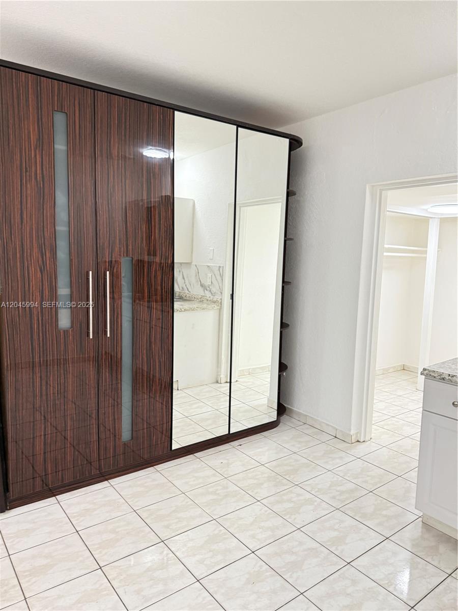A room features a large dark wood wardrobe with mirrored doors and tiled flooring — HALLANDALE BEACH, FL
