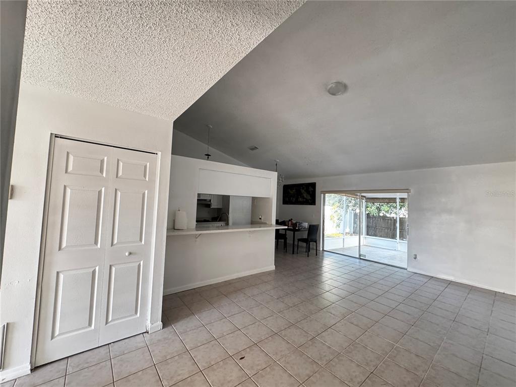 A living room with tile floors, a kitchen pass-through, and sliding glass doors to a patio — 9213 CAMINO VILLA BOULEVARD, TAMPA, FL