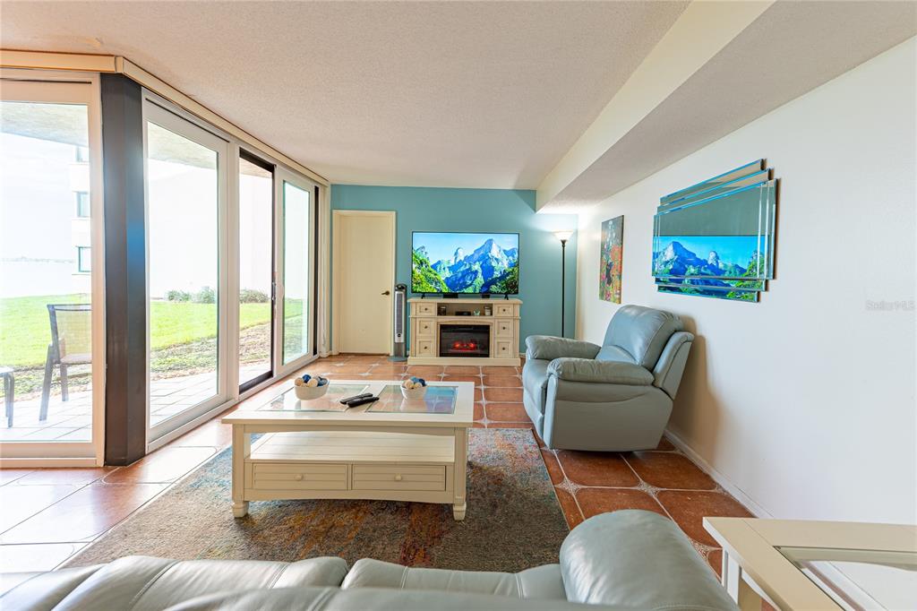 A living room features a light blue accent wall, tile flooring, and sliding glass doors — 5541 PUERTA DEL SOL BOULEVARD S UNIT 116, ST PETERSBURG, FL