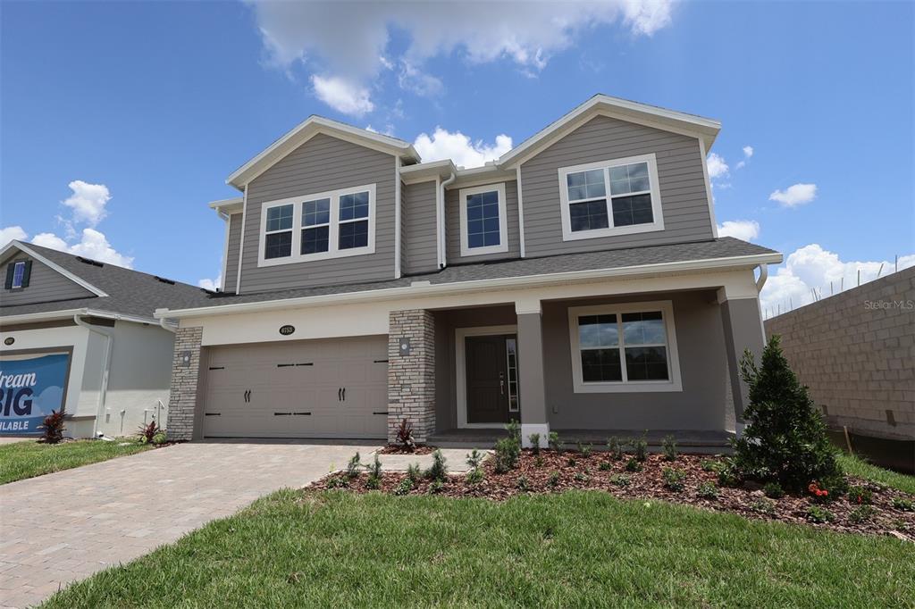 A modern kitchen features white cabinetry, stainless steel appliances, a center island, and wood-look flooring — 6753 YELLOW WARBLER BEND, ST CLOUD, FL