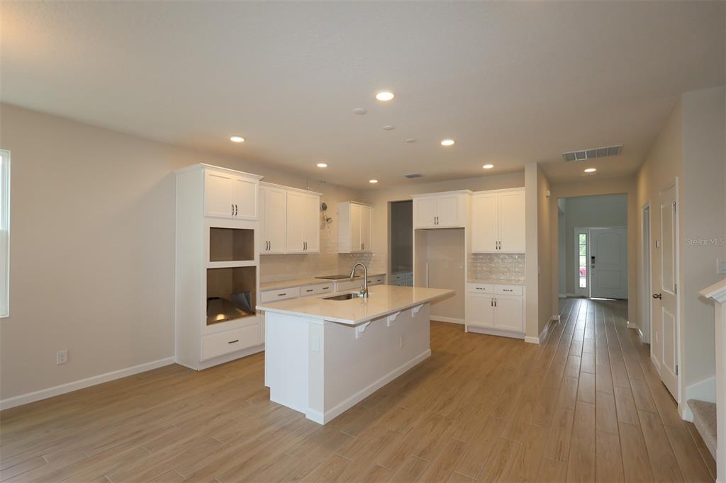 An empty living room features light wood-look tile flooring, recessed lighting, and a sliding glass door — 6753 YELLOW WARBLER BEND, ST CLOUD, FL