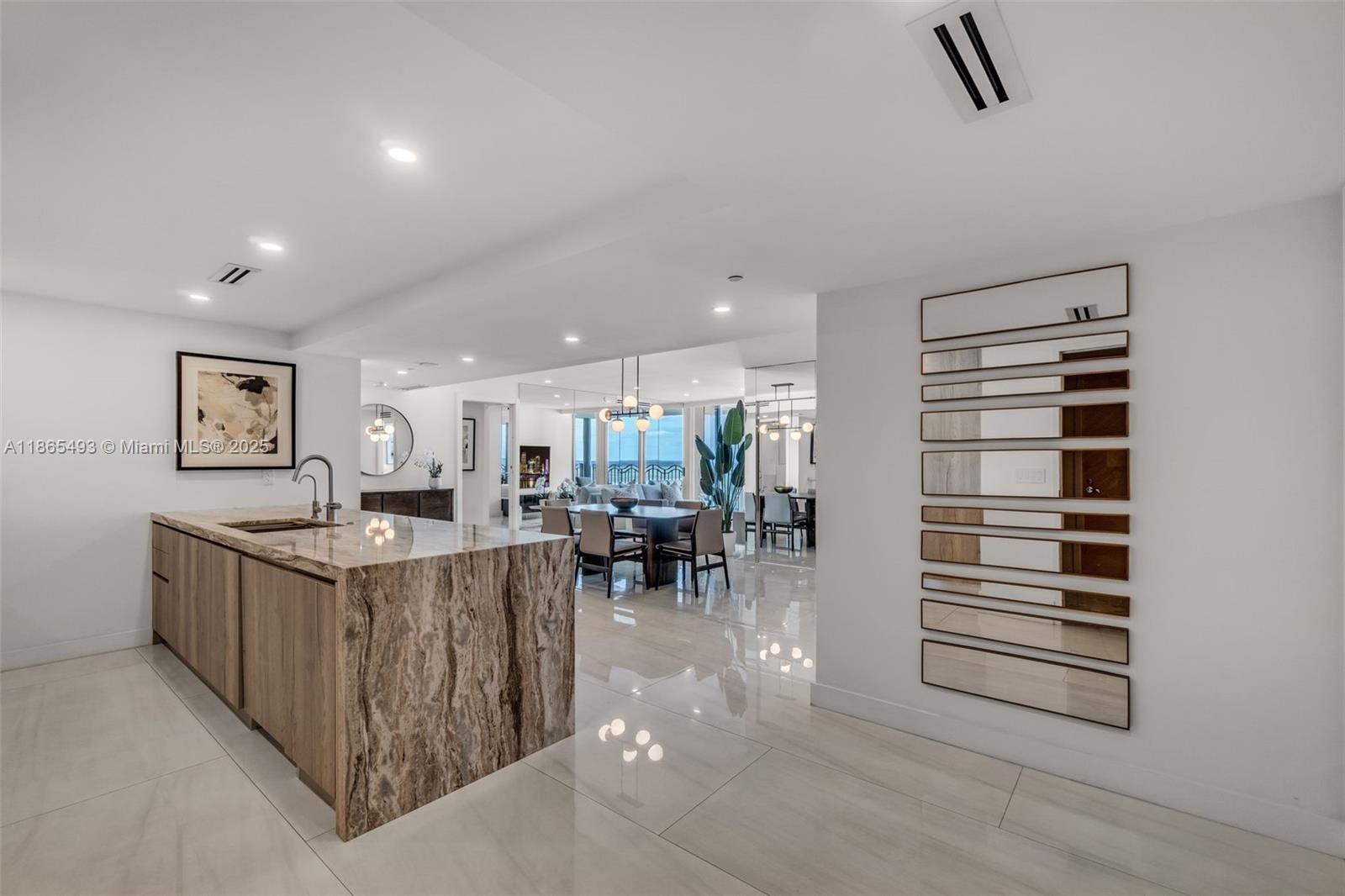 A modern kitchen with a marble island overlooks an open-concept dining and living area — 1500 Ocean Drive # 1003, Miami Beach FL 33139, MIAMI BEACH, FL