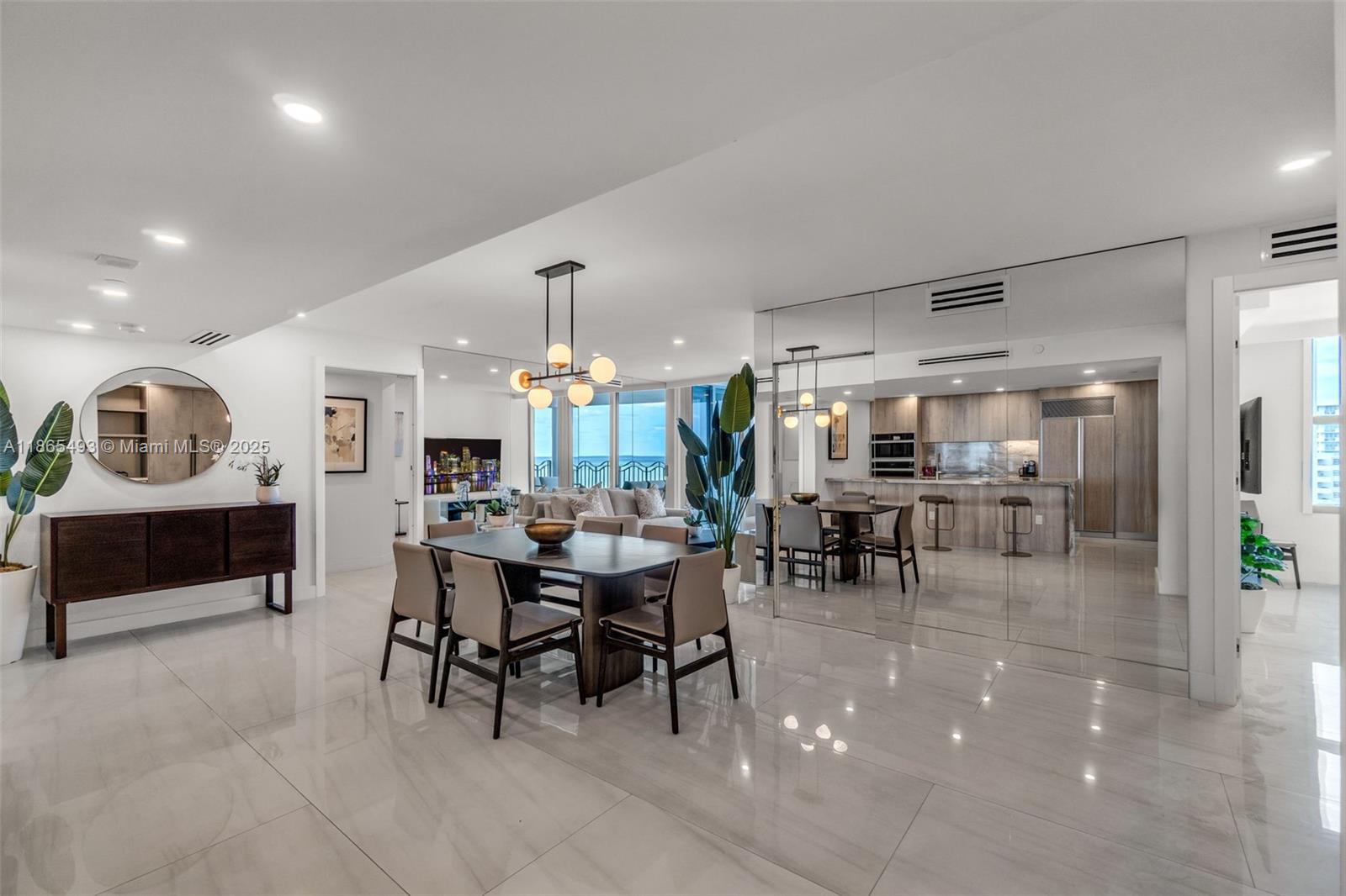 A dining area with a modern chandelier, dark wood table, and mirrored wall in an apartment — 1500 Ocean Drive # 1003, Miami Beach FL 33139, MIAMI BEACH, FL