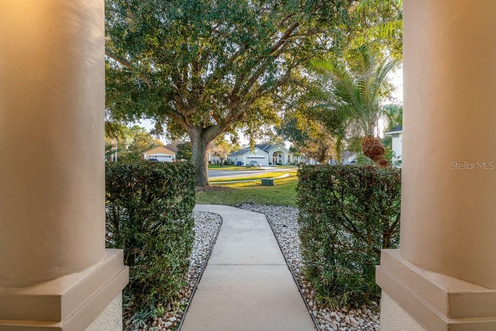 A view from a covered entryway looking out toward a suburban street and trees — 4019 GEORGETOWN COURT, ST CLOUD, FL