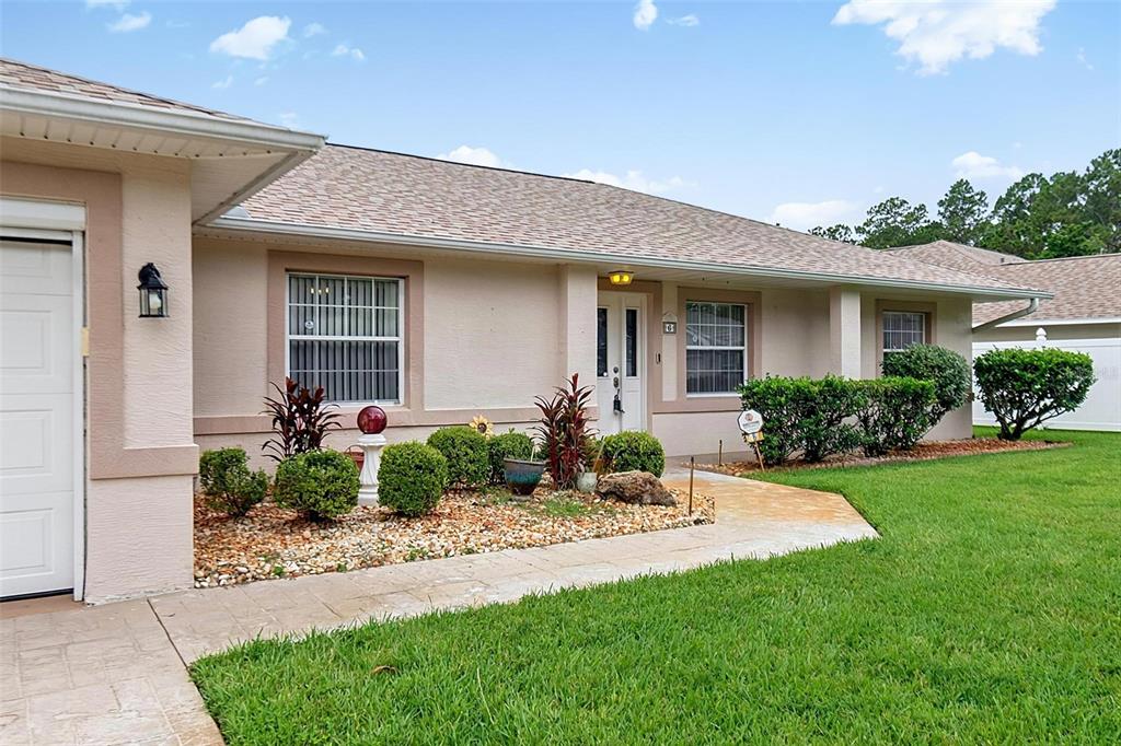 A single-story house with a beige exterior, a paved walkway, and a manicured front lawn — 6 WILMONT PLACE, PALM COAST, FL
