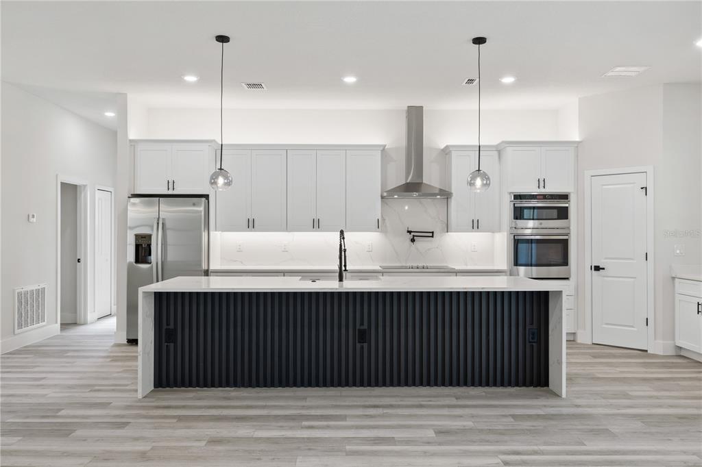 A modern kitchen features white cabinetry, a dark slatted island, and stainless steel appliances — 8268 SW 122ND AVENUE, DUNNELLON, FL