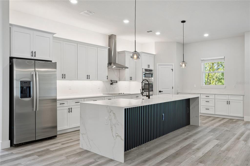 A modern kitchen features white cabinetry, a marble-topped island with black slats, and stainless appliances — 8268 SW 122ND AVENUE, DUNNELLON, FL