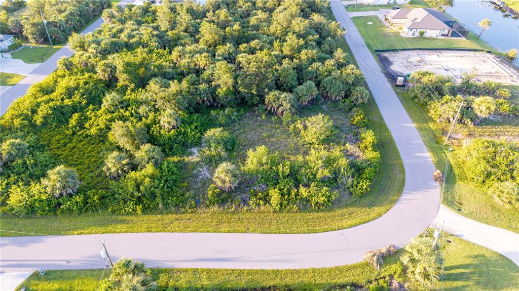 An aerial view shows a vacant, wooded residential lot bordered by paved roads — 9419 IMPALA CIRCLE, PORT CHARLOTTE, FL