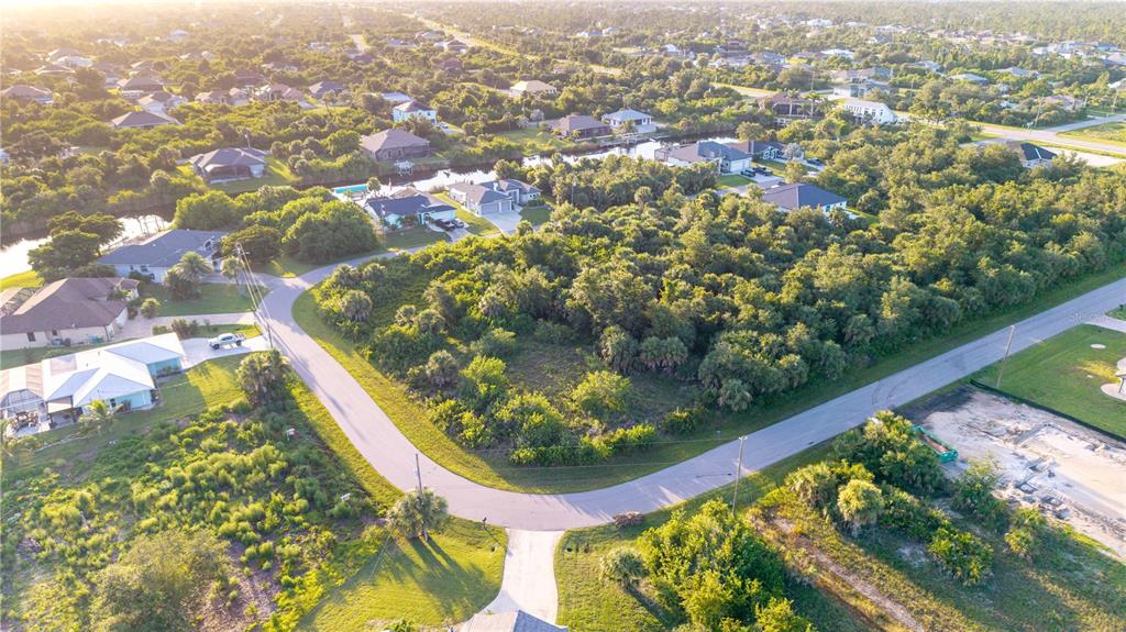 An aerial view shows a vacant, tree-covered residential lot situated on a curved suburban street — 9419 IMPALA CIRCLE, PORT CHARLOTTE, FL