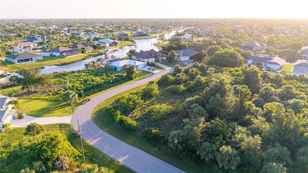 An aerial view shows a curved road winding through a residential neighborhood with canal access — 9419 IMPALA CIRCLE, PORT CHARLOTTE, FL