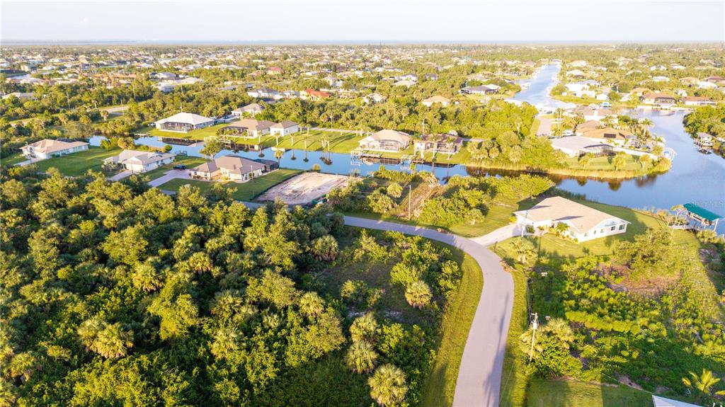 An aerial view shows houses along a canal surrounded by dense green vegetation — 9419 IMPALA CIRCLE, PORT CHARLOTTE, FL