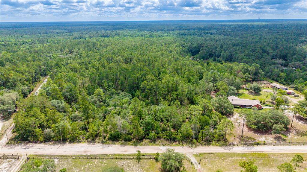 An aerial view shows a wooded lot with a house and a dirt road — GOLDEN OAK LANE, KEYSTONE HEIGHTS, FL