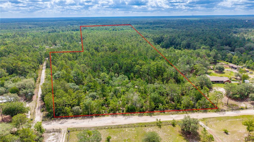 An aerial view shows a wooded lot outlined in red next to a dirt road — GOLDEN OAK LANE, KEYSTONE HEIGHTS, FL