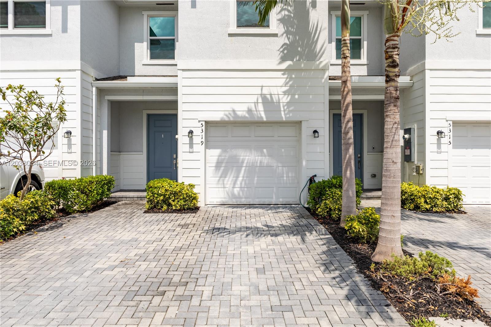 The exterior view shows two adjacent townhomes with paved driveways, white siding, and blue doors — 5319 Flannigan Way # 0, Lake Worth FL 33463, LAKE WORTH, FL