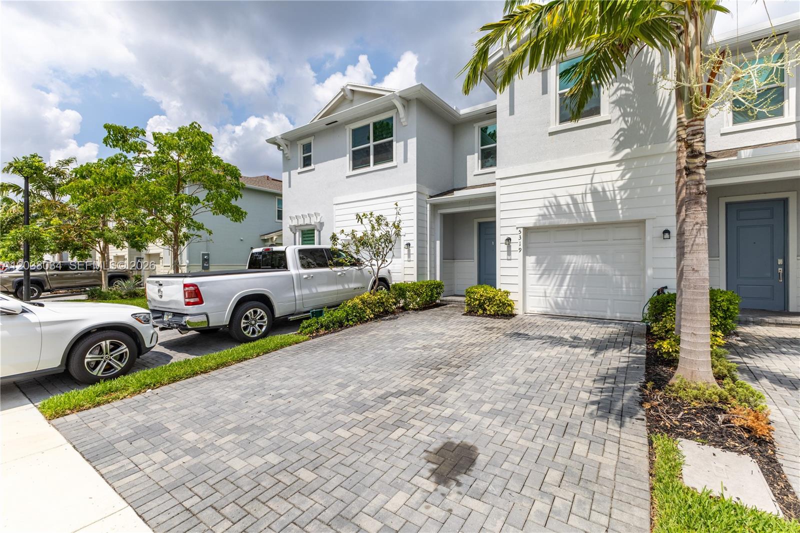 A two-story house with a paved driveway, a white garage door, and a palm tree — 5319 Flannigan Way # 0, Lake Worth FL 33463, LAKE WORTH, FL