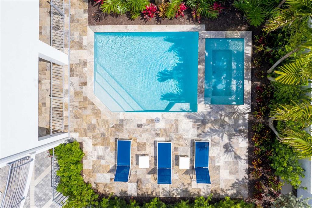 An aerial view shows a rectangular swimming pool and spa surrounded by a stone patio — 1140 SEASIDE DRIVE UNIT 101, SARASOTA, FL