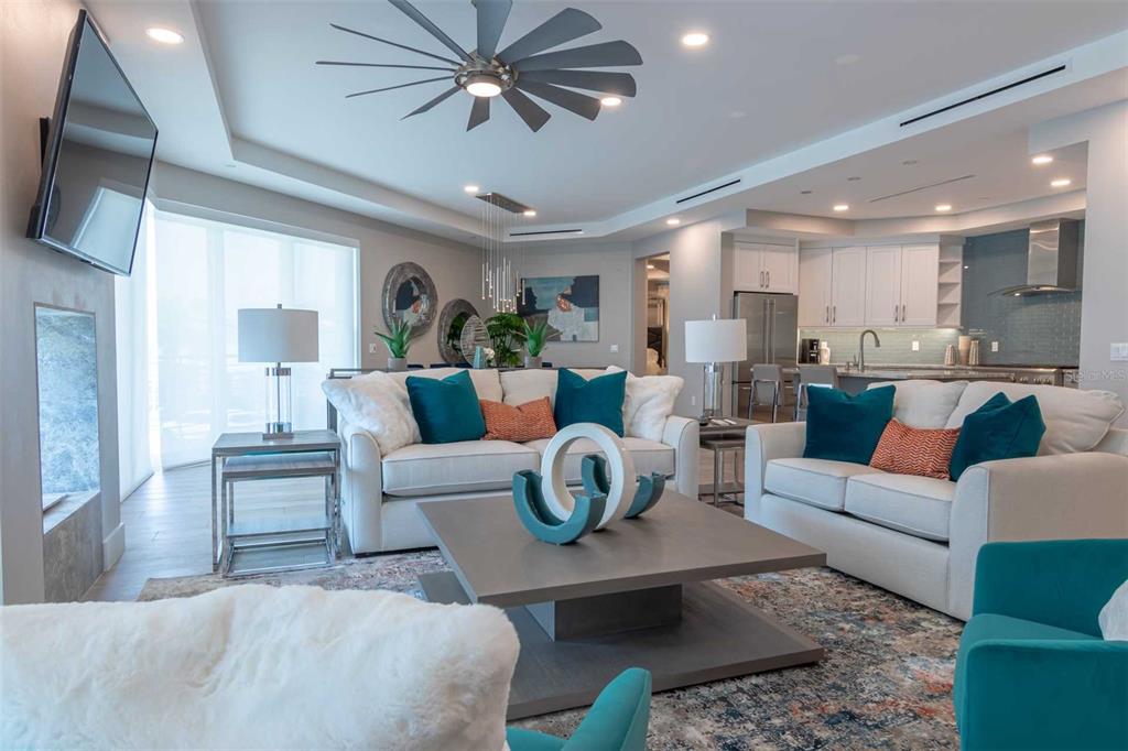 A modern living room features white sofas, a square coffee table, and an open kitchen — 1140 SEASIDE DRIVE UNIT 101, SARASOTA, FL