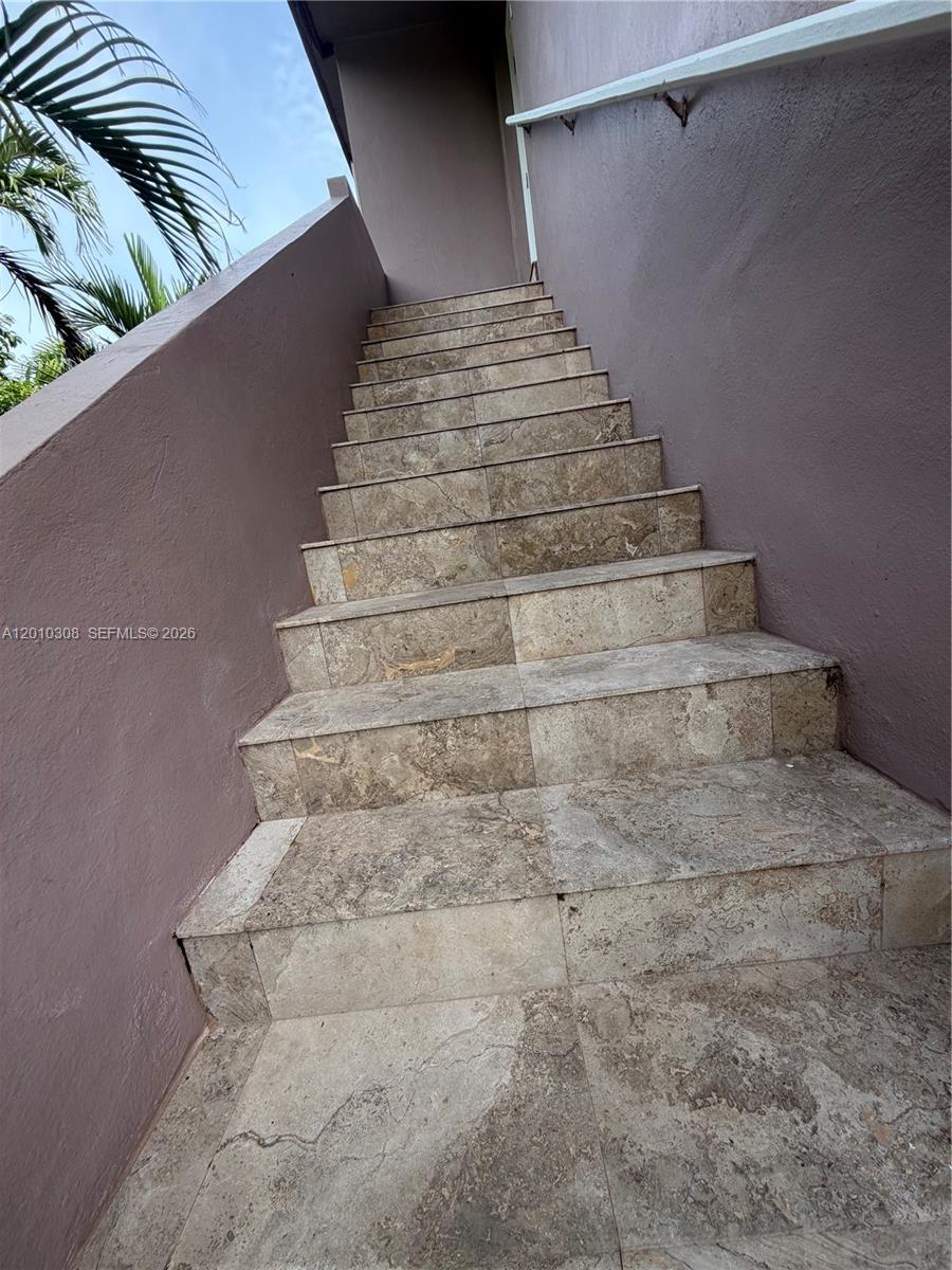 An outdoor staircase with stone-tiled steps leads up to a landing against a purple wall — 6201 SW 21st St # 6203, Miami FL 33155, MIAMI, FL
