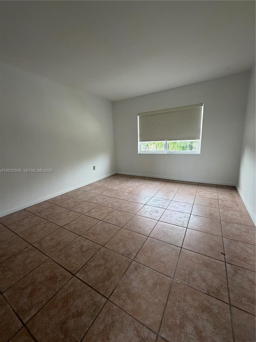 An empty bedroom features white walls, a single window with a shade, and tiled flooring — 6201 SW 21st St # 6203, Miami FL 33155, MIAMI, FL