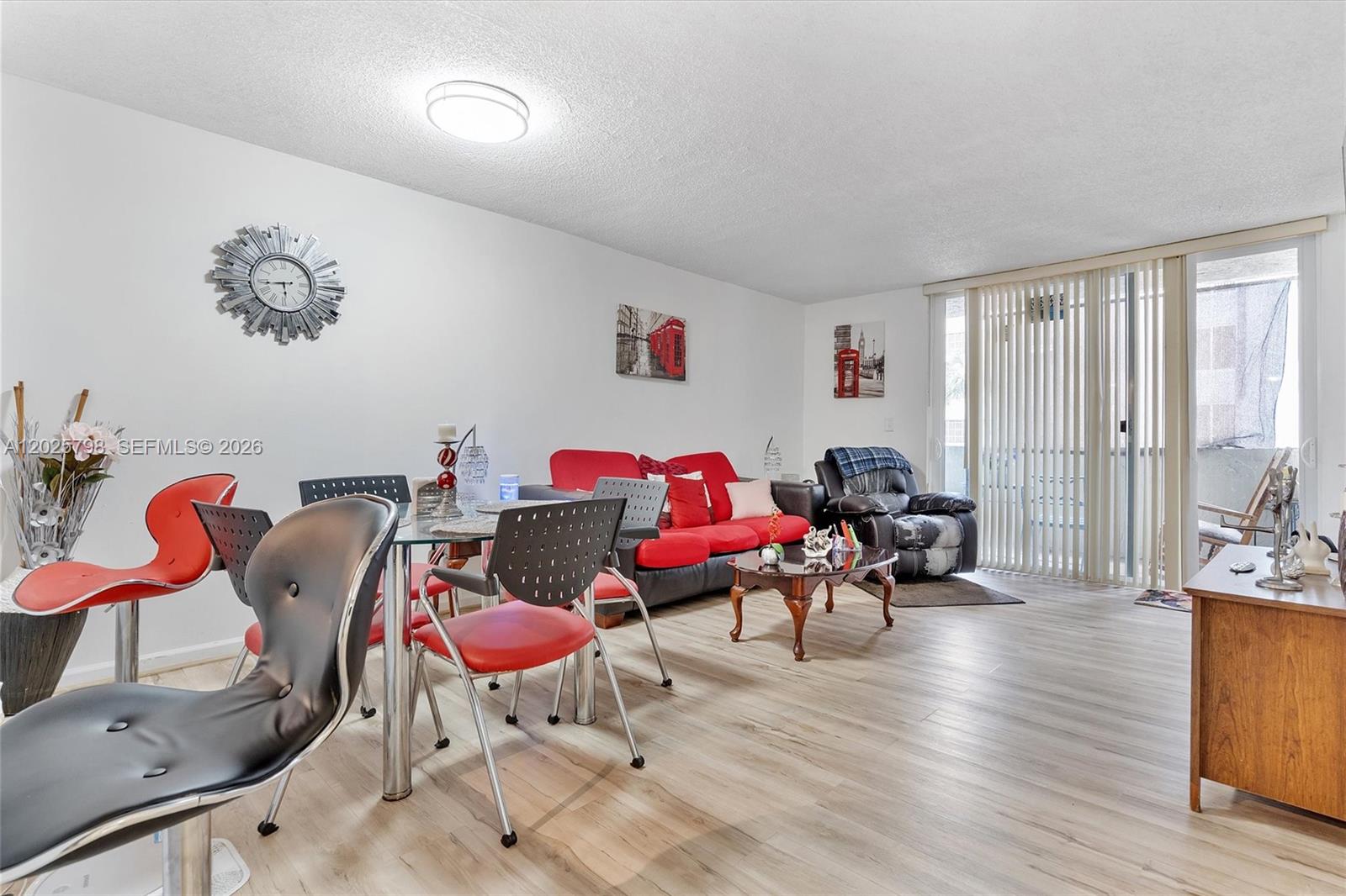 A living and dining area features wood-look flooring, a red sofa, and a glass table — 10000 NW 80th Ct # 2245, Hialeah Gardens FL 33016, HIALEAH GARDENS, FL