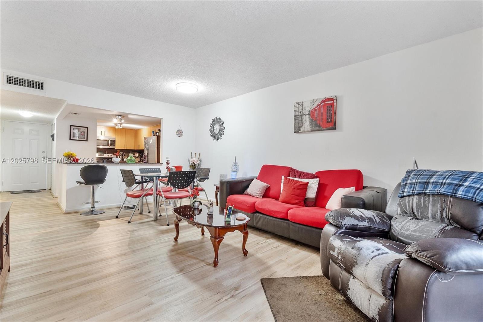 A living room and dining area feature light wood floors, a red sofa, and kitchen access — 10000 NW 80th Ct # 2245, Hialeah Gardens FL 33016, HIALEAH GARDENS, FL