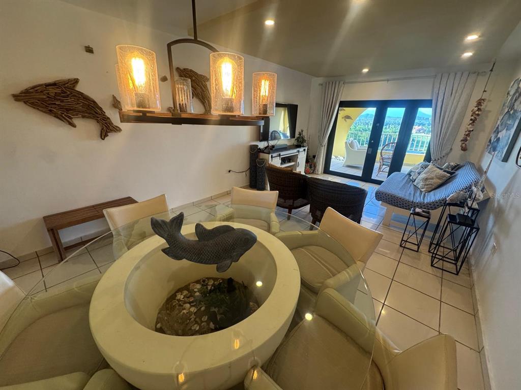 A dining area with a glass-topped table and a living space with a balcony view — 295 PALMAS INNWAY UNIT 323, HUMACAO, PR
