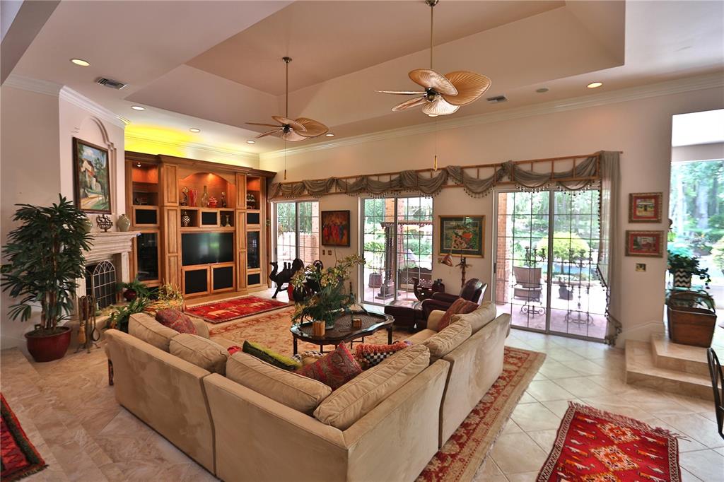 A spacious living room features a large sectional sofa, built-in cabinetry, and sliding glass doors — 1300 SW 43RD PLACE, OCALA, FL