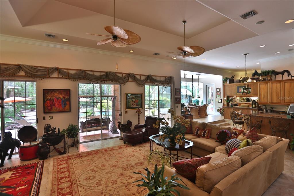 A spacious living room with tile floors, a large sectional sofa, and sliding glass doors — 1300 SW 43RD PLACE, OCALA, FL