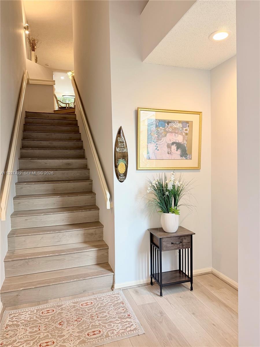 A staircase with wood-look steps leads to an upper landing next to a small table — 905 Mainsail Circle # 905, Jupiter FL 33477, JUPITER, FL