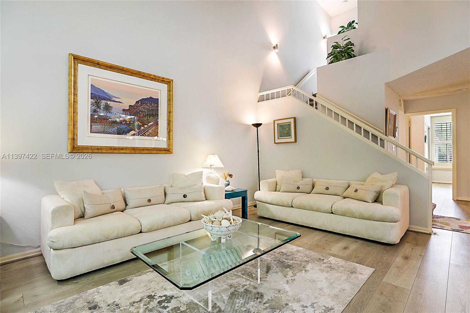 A living room features two white sofas, a glass coffee table, and a staircase — 905 Mainsail Circle # 905, Jupiter FL 33477, JUPITER, FL