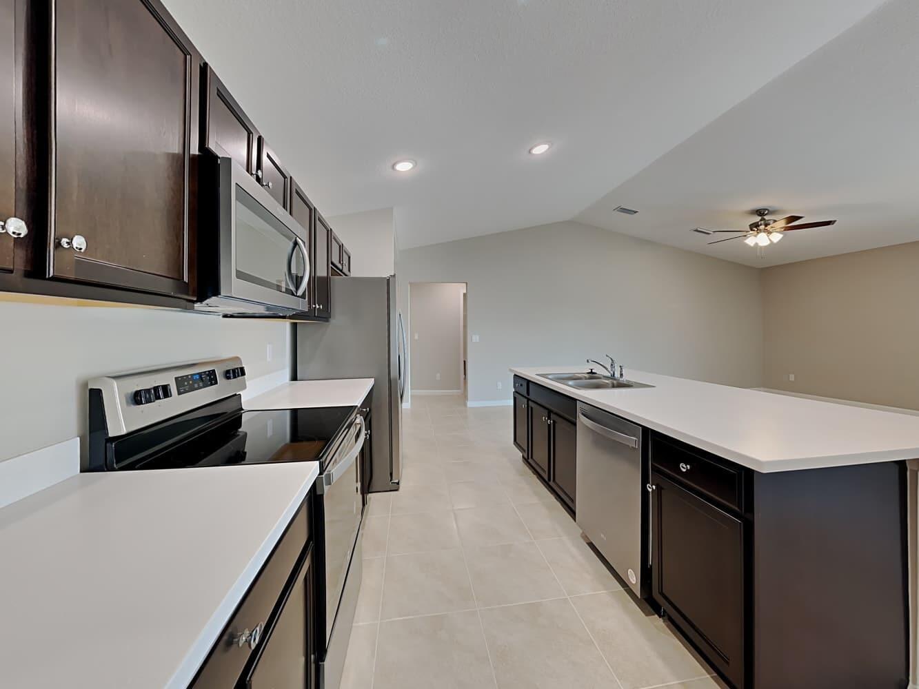 A kitchen features dark wood cabinets, stainless steel appliances, and a white quartz island countertop — PORT ST. LUCIE, FL