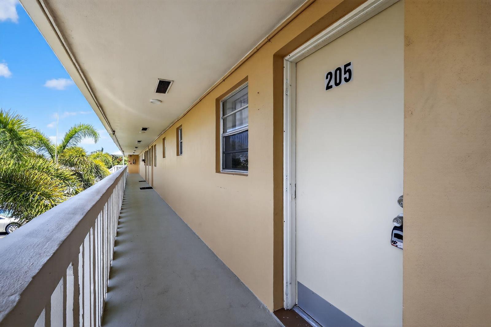 An exterior walkway leads past a white door labeled 205 with a palm tree view — 2152 NE 1st Way # 205, Boynton Beach FL 33435, BOYNTON BEACH, FL