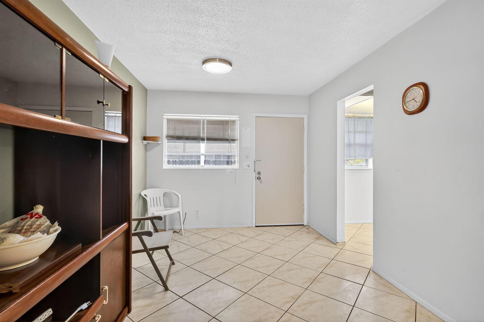 A room with light-colored tile flooring, a window, a door, and a wooden shelving unit — 2152 NE 1st Way # 205, Boynton Beach FL 33435, BOYNTON BEACH, FL