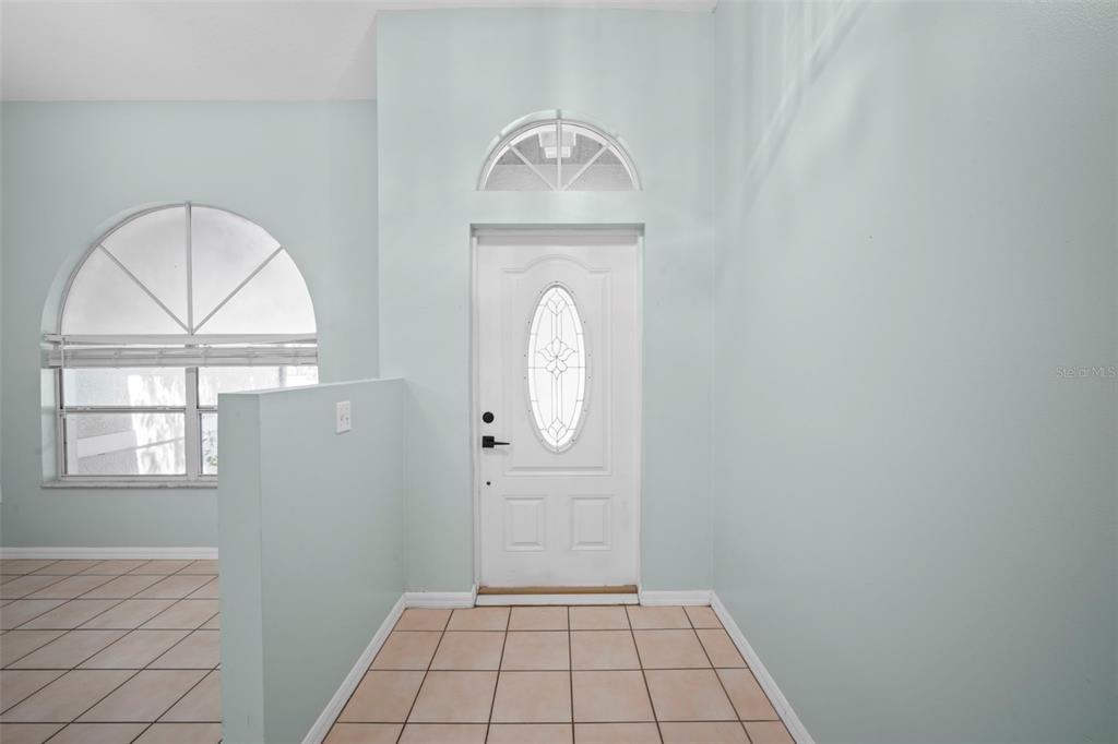 An entryway features a white front door with a glass insert, tile flooring, and light-colored walls — 1724 BARKER STREET NE, PALM BAY, FL
