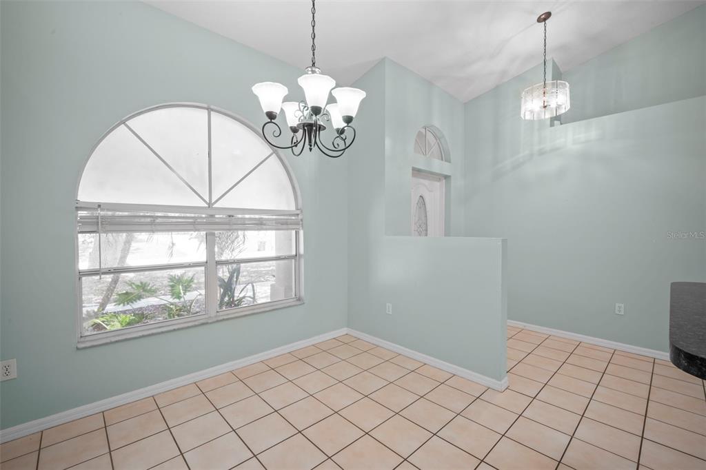 A dining area features light blue walls, tile flooring, a large arched window, and two chandeliers — 1724 BARKER STREET NE, PALM BAY, FL