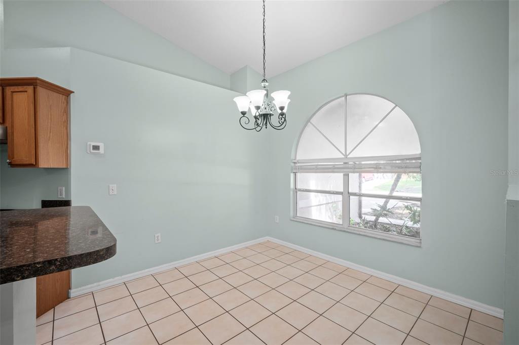 A dining area with light green walls, tile flooring, a chandelier, and an arched window — 1724 BARKER STREET NE, PALM BAY, FL