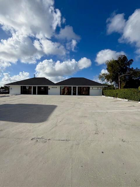 A single-story commercial building with a large parking lot under a blue sky — 4259 10th Avenue N, FL 33461, FL