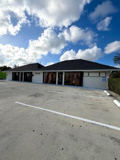 A single-story commercial building with a parking lot under a bright, cloudy sky — 4259 10th Avenue N, FL 33461, FL