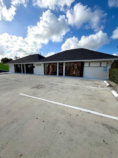 A single-story commercial building with a parking lot in front under a blue sky — 4259 10th Avenue N, FL 33461, FL