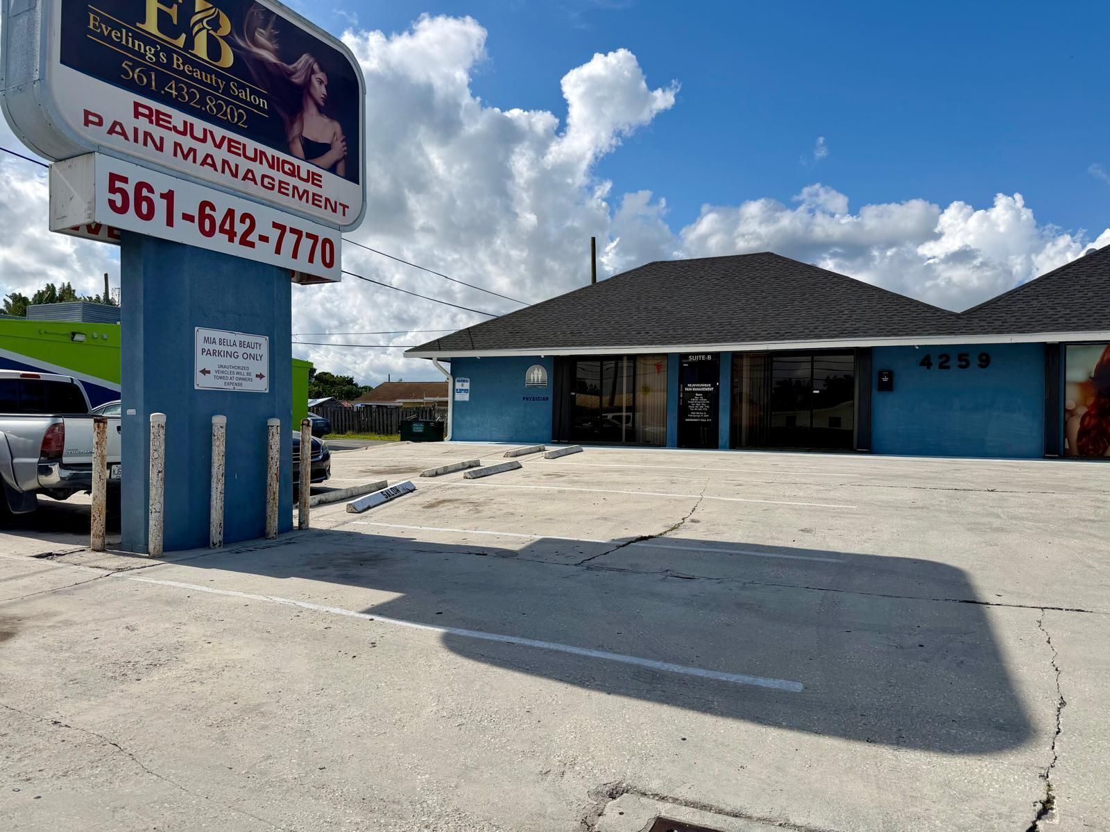 A blue commercial building with a parking lot and a large sign in the foreground — 4259 10th Avenue N, FL 33461, FL