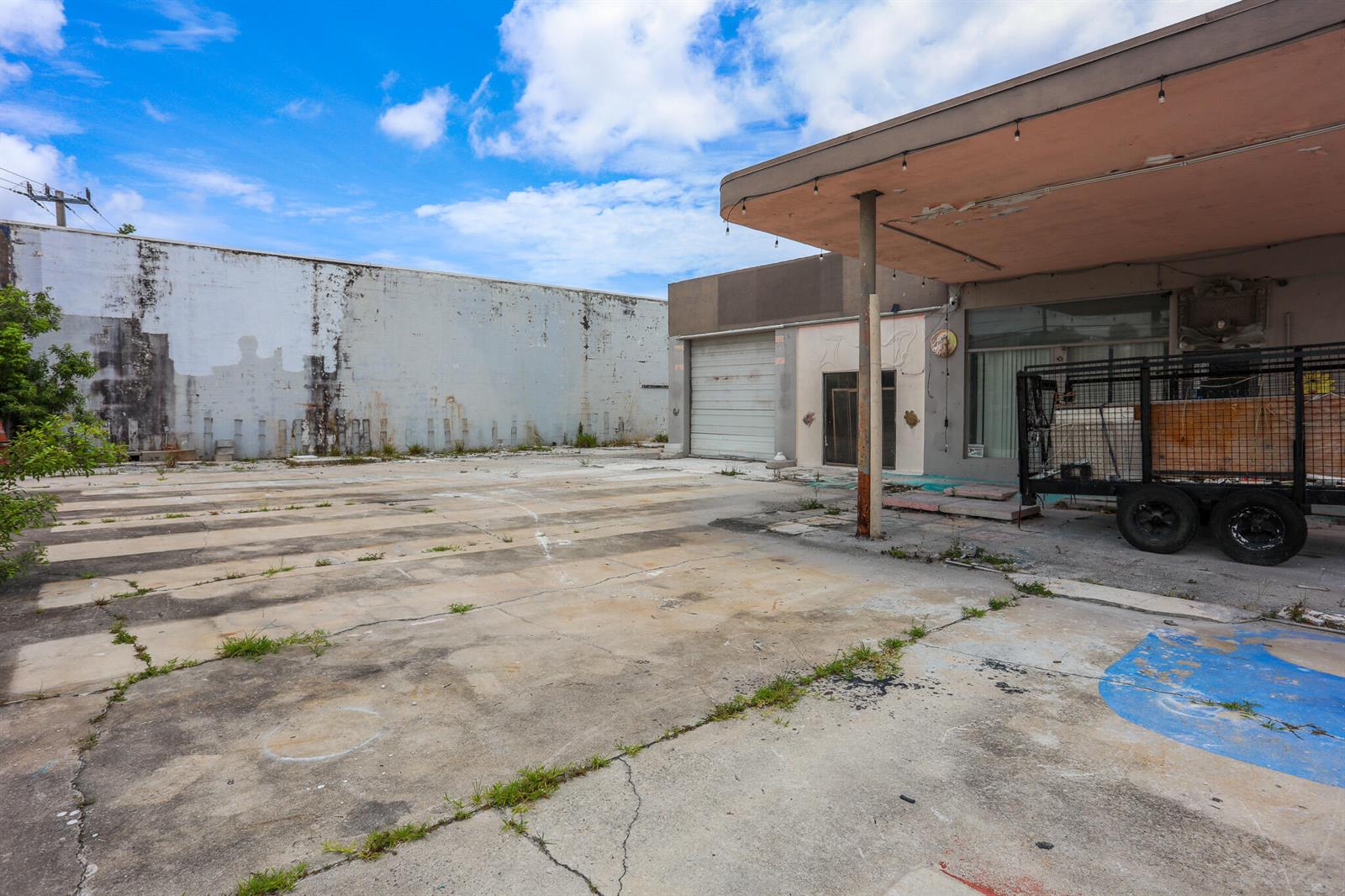 An exterior view shows a weathered concrete lot with a trailer parked under a canopy — 1620 S Dixie Highway, Pompano Beach FL 33060, POMPANO BEACH, FL