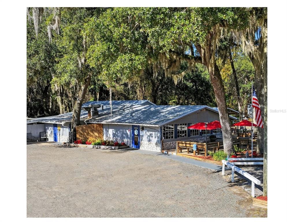 A single-story commercial building with a metal roof, gravel parking lot, and outdoor patio seating — 2396 N C 470, LAKE PANASOFFKEE, FL