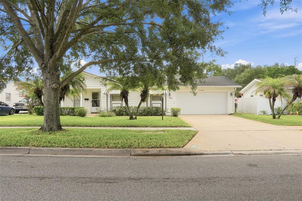 A single-story white house with a two-car garage and a large tree in the yard — 1013 SUNWOOD LANE, ORLANDO, FL