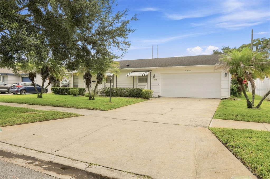 A single-story white house with a two-car garage, a concrete driveway, and palm trees — 1013 SUNWOOD LANE, ORLANDO, FL