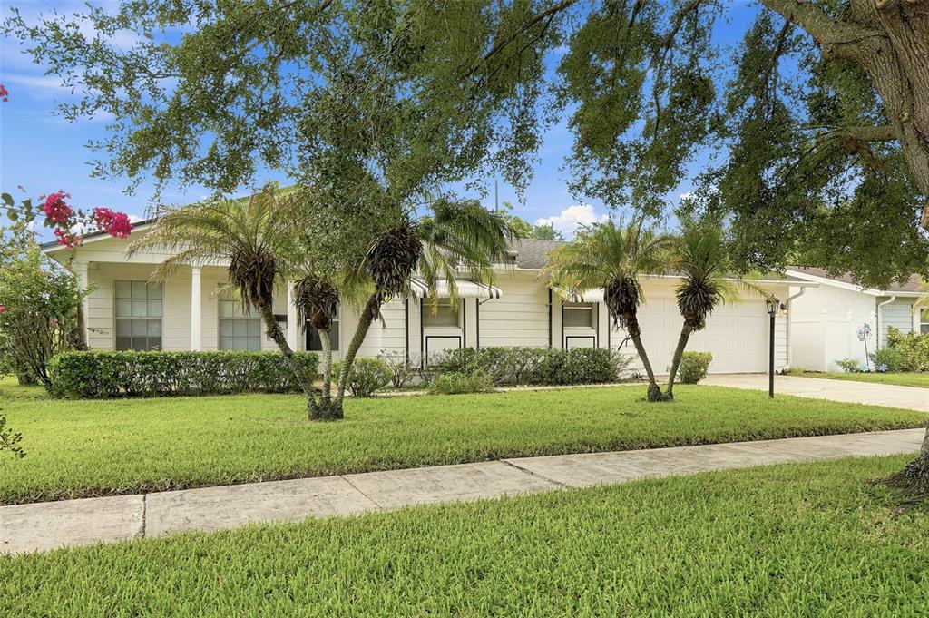 A single-story white house with a front porch, palm trees, and a two-car garage — 1013 SUNWOOD LANE, ORLANDO, FL